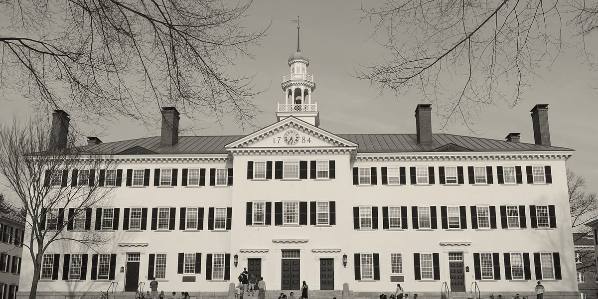 Dartmouth Hall, a white Georgian building with a bell tower, students on the steps.